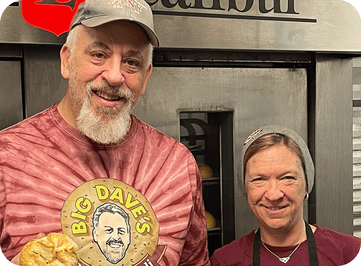 Big Dave’s Bagels & Deli owners smiling and holding fresh bagels