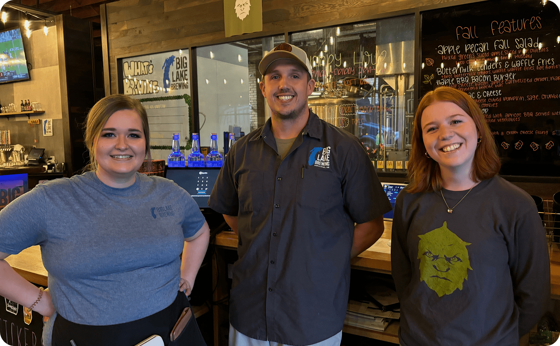 Three Big Lake Brewing team members smiling in front of the bar