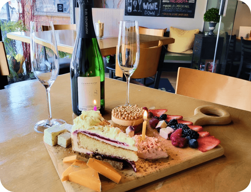 A table set with wine, cake, fruit, and cheese