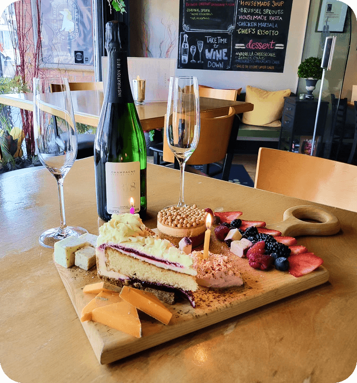 A table set with wine, cake, fruit, and cheese