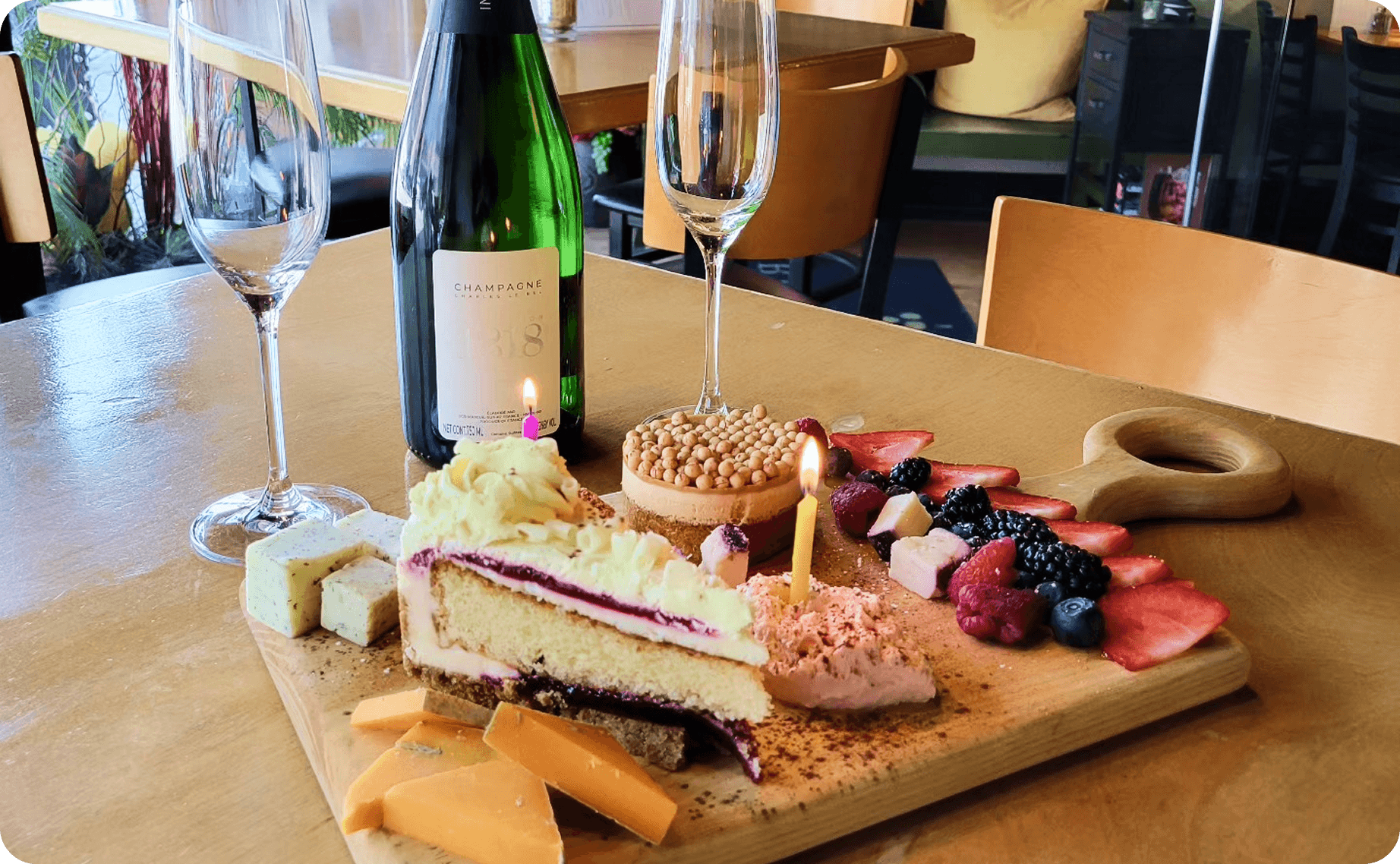 A table set with wine, cake, fruit, and cheese
