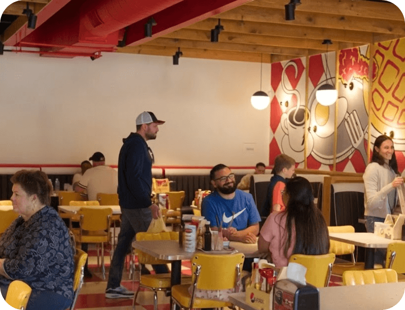 Un mesero conversa con comensales en Breakfast Brothers