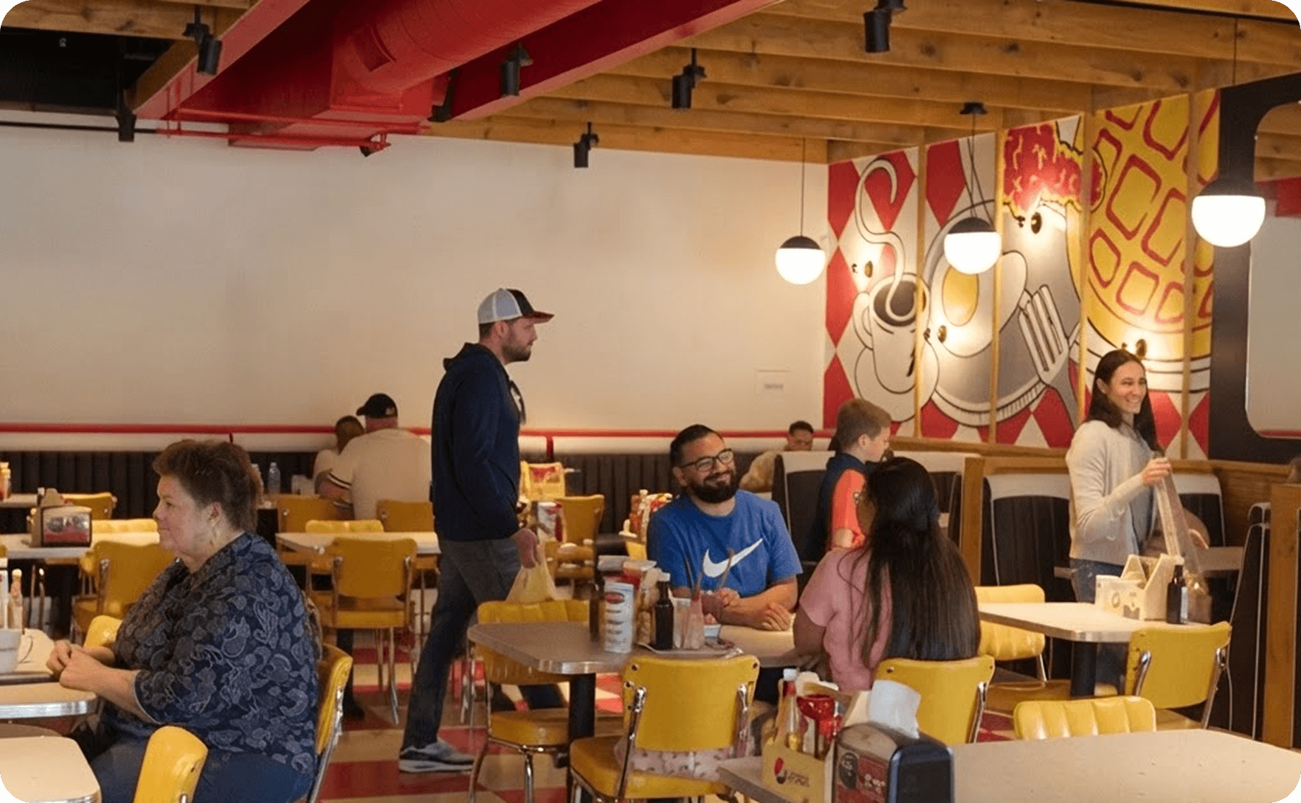 Un mesero conversa con comensales en Breakfast Brothers