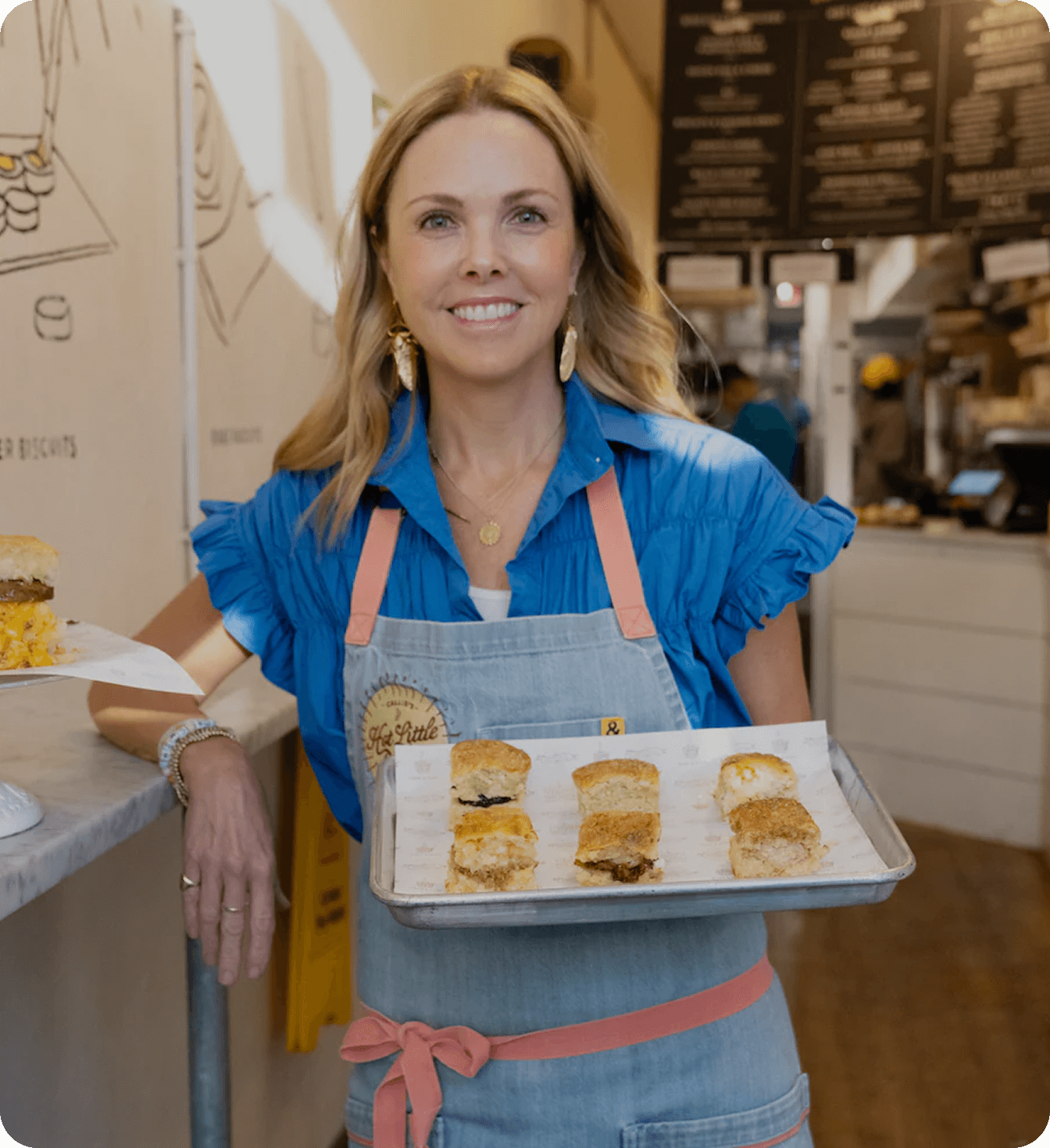 Callie’s Hot Little Biscuit founder holding tray of fresh biscuits in shop