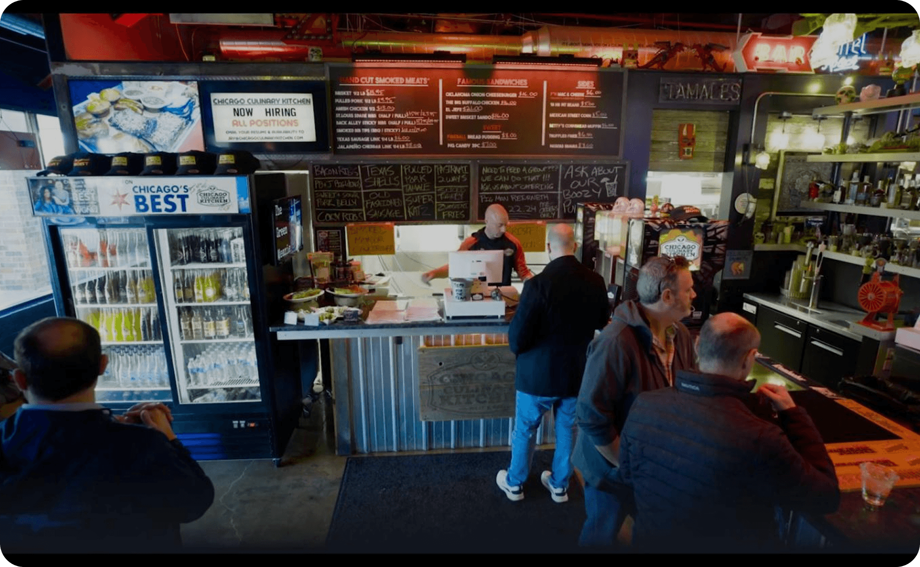 Guests ordering at the counter at Chicago Culinary Kitchen, with the full menu board and a “Now Hiring” sign behind the register