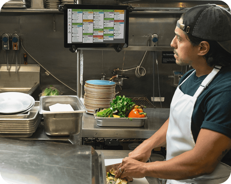 A restaurant kitchen worker views orders on a KDS screen