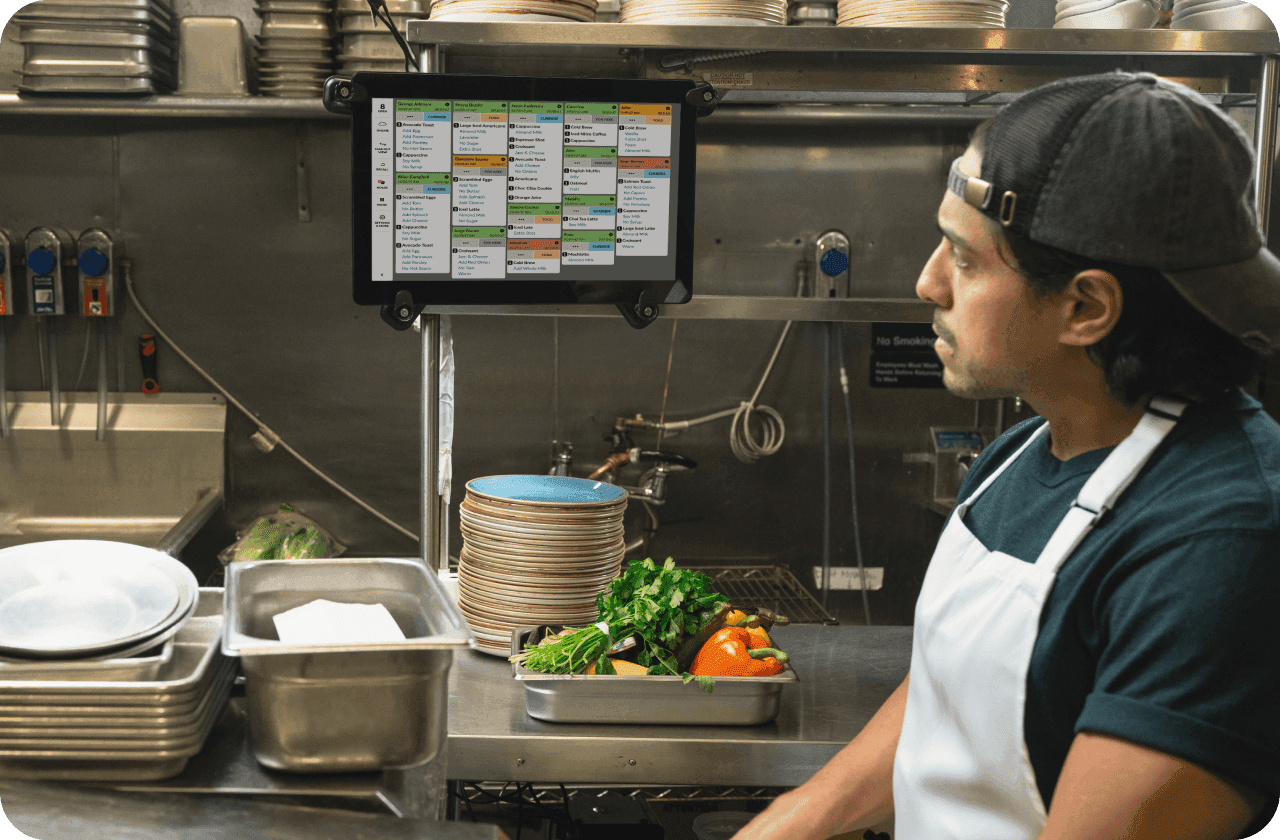 A restaurant kitchen worker views orders on a KDS screen