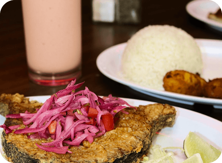 Fried fish with pickled onions, rice, and tostones at Cacique Restaurant