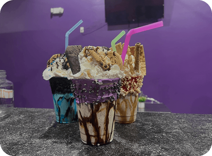 Colorful milkshakes topped with cookies, whipped cream, and chocolate drizzle