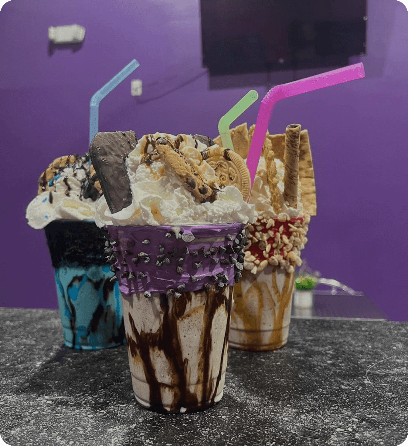 Colorful milkshakes topped with cookies, whipped cream, and chocolate drizzle