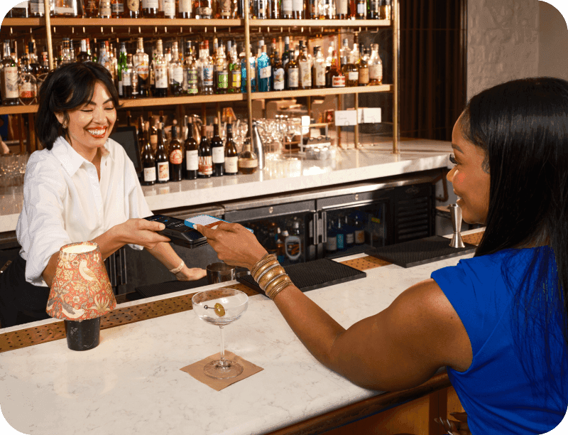 A restaurant customer taps to pay the bill on a handheld POS device