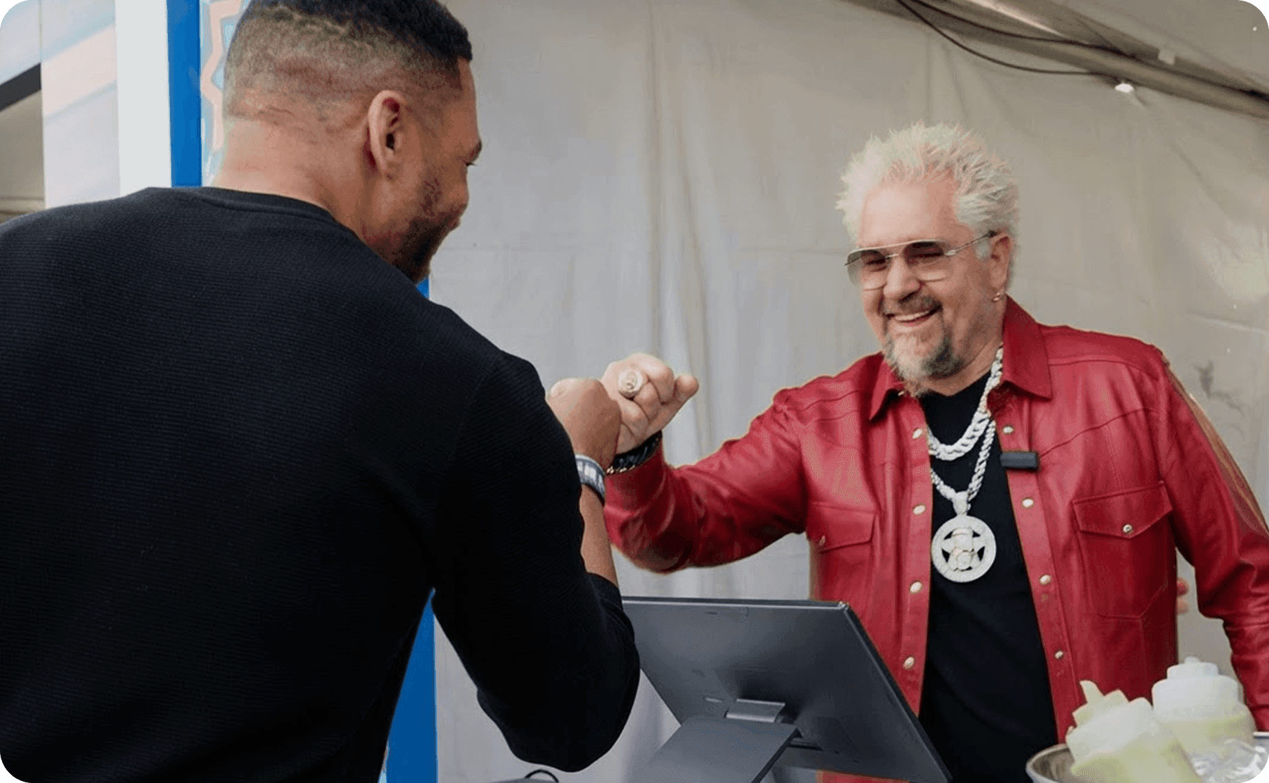 Guy Fieri fist-bumping a vendor at a SpotOn POS station at Guy’s Flavortown Tailgate