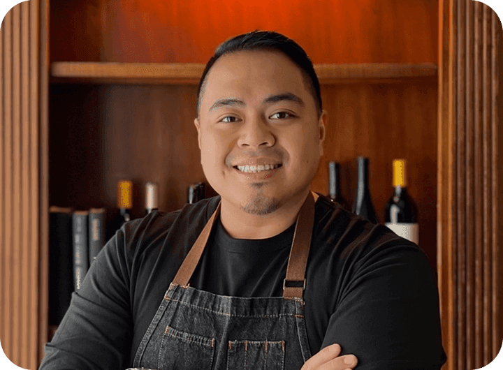 JB Balingit, owner of The Hideout Kitchen, smiling in black apron