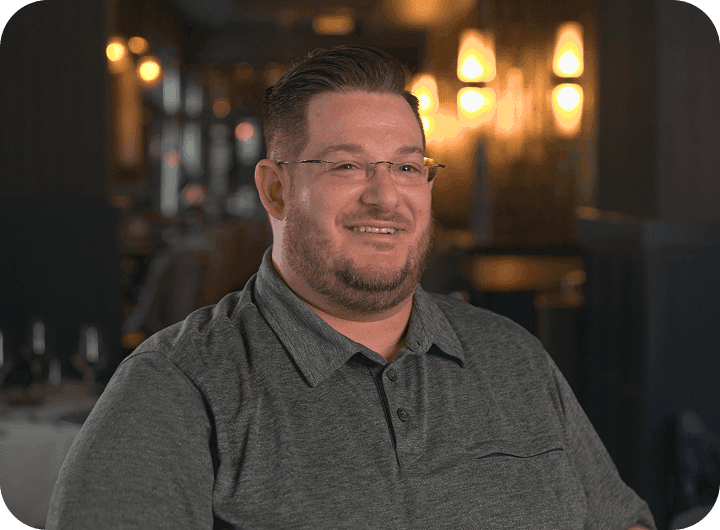 Jonathan Gillespie talking in front of a restaurant dining room
