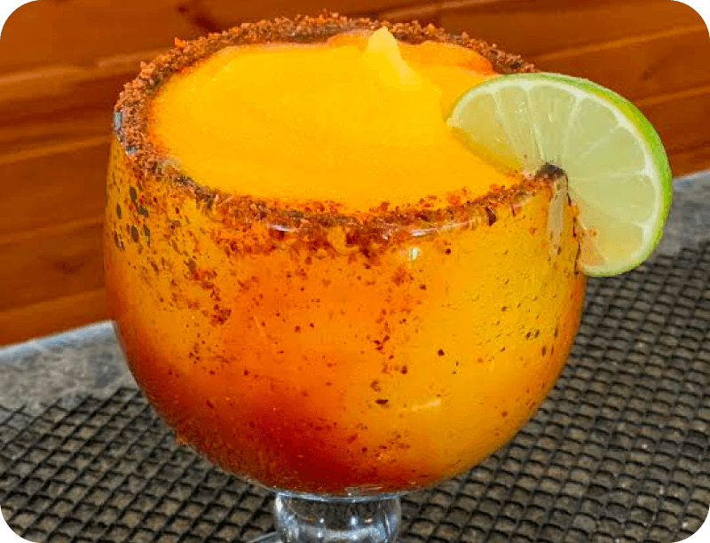 A frozen mango margarita with a chili-salt rim and a lime wheel at La Chiva Loka