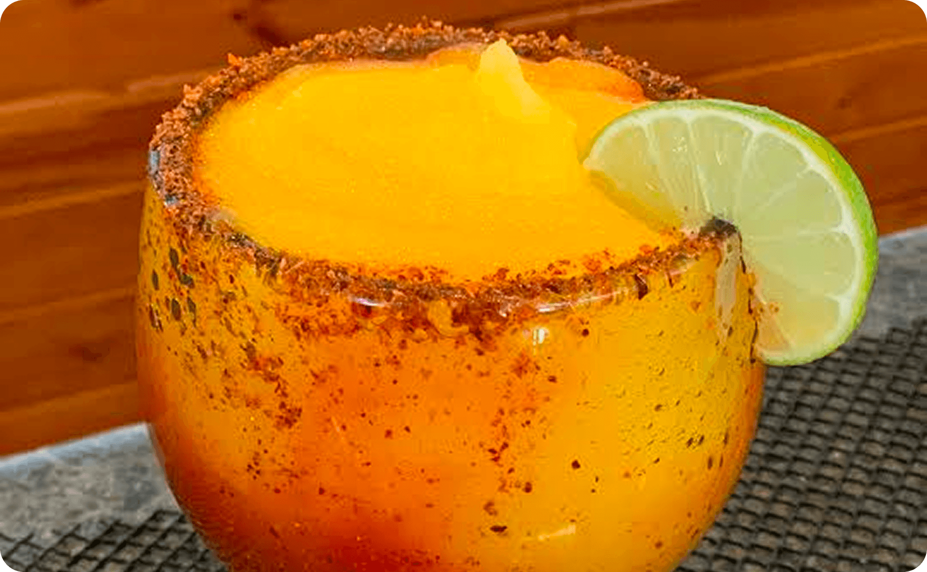 A frozen mango margarita with a chili-salt rim and a lime wheel at La Chiva Loka