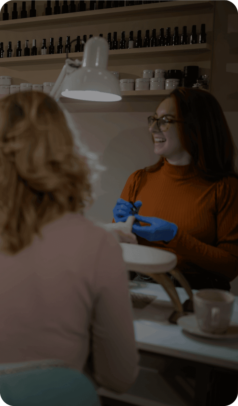 A nail salon worker works with a customer