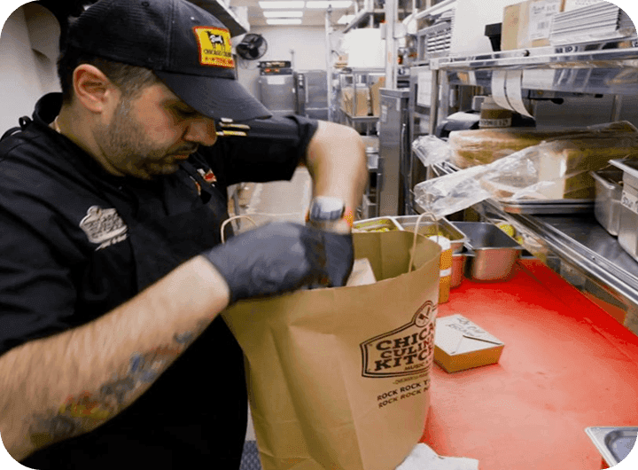 An employee bagging an online order in a branded Chicago Culinary Kitchen bag