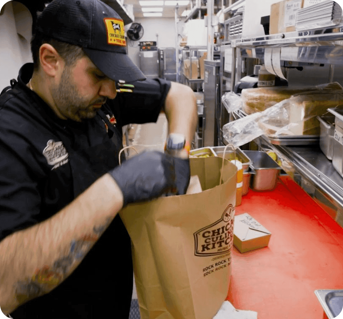 An employee bagging an online order in a branded Chicago Culinary Kitchen bag