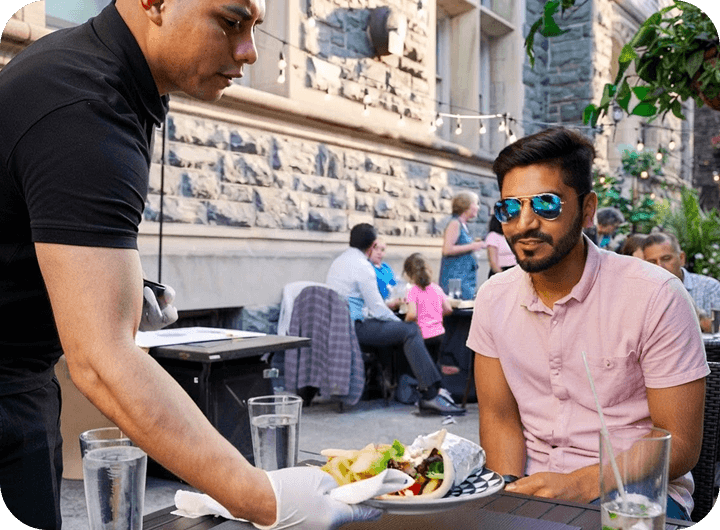 A server delivers food to a guest on the patio at Urban Roast