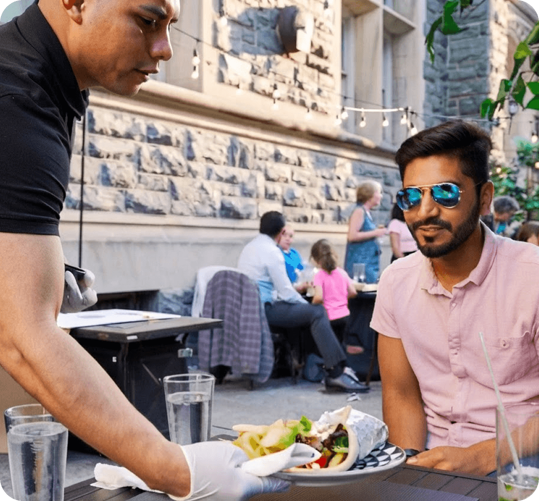 A server delivers food to a guest on the patio at Urban Roast