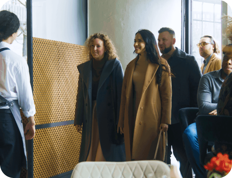 A restaurant host greets guest and checks their place in line using  restaurant waitlist software