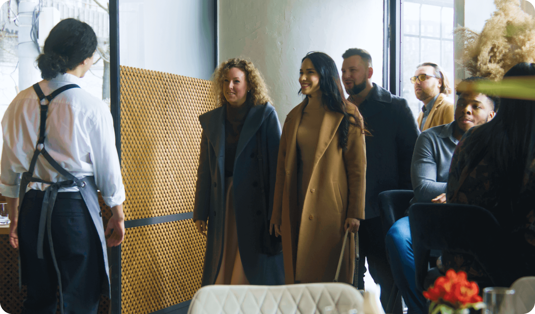 A restaurant host greets guest and checks their place in line using  restaurant waitlist software