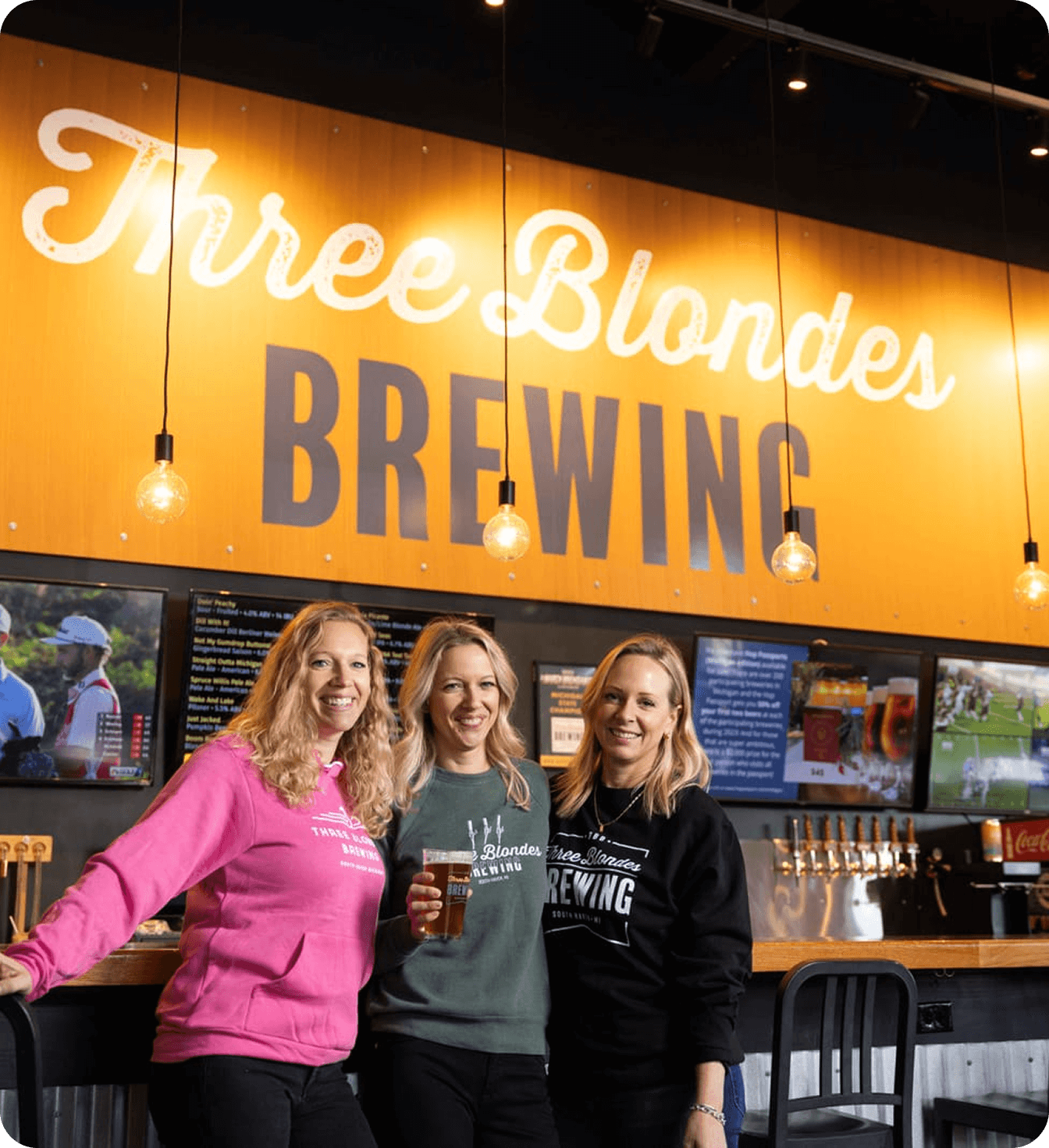 Three Blondes Brewing owners standing behind bar inside brewery taproom