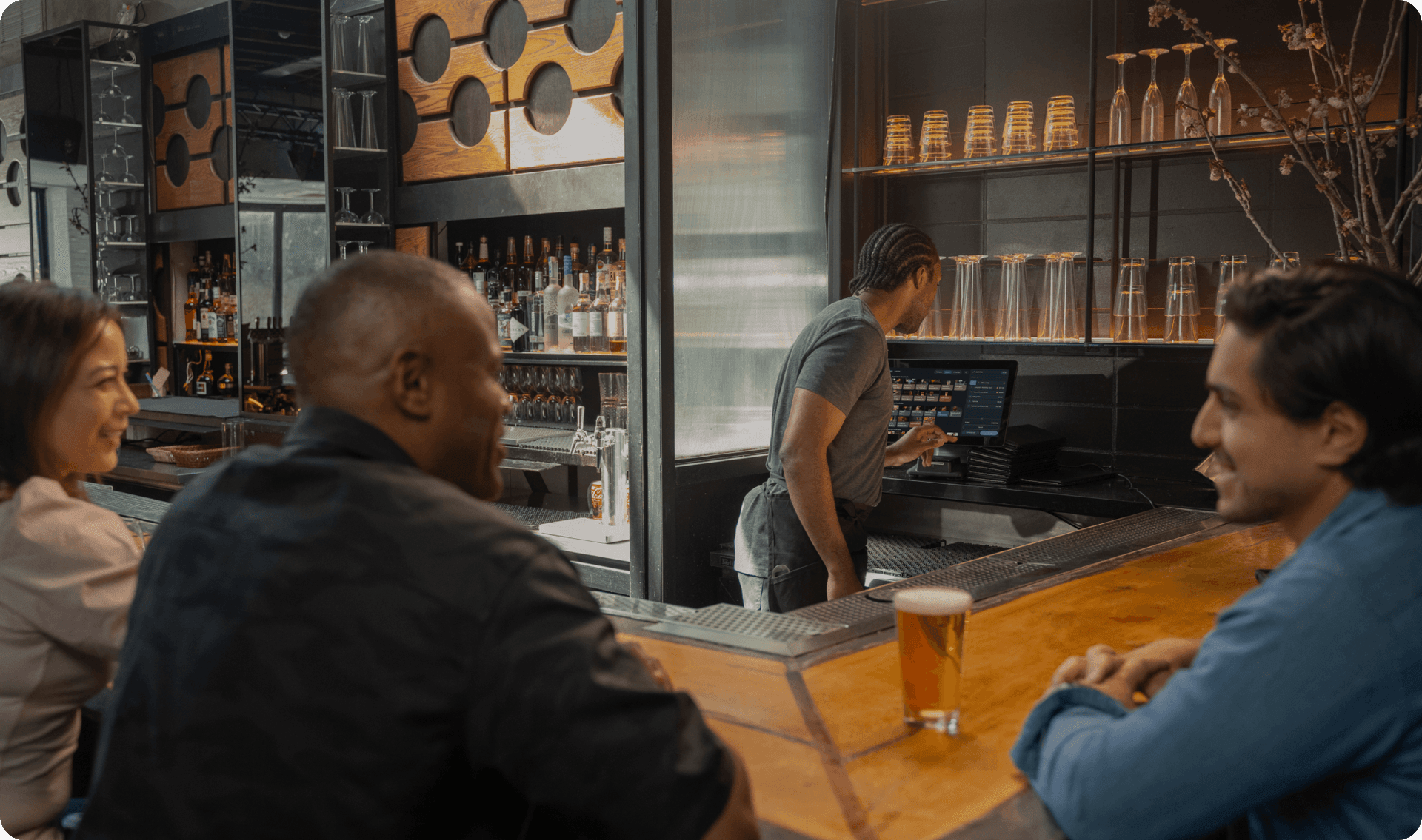 Bartender mixing a drink while serving a guest at a busy bar