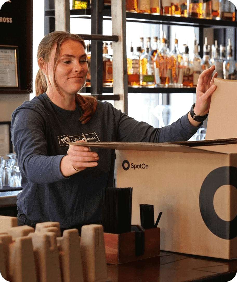 SpotOn employee unpacking SpotOn POS equipment at the bar