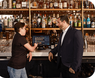 SpotOn rep shows a restaurant owner something on a laptop at a table