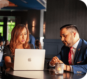SpotOn rep shows a restaurant owner something on a laptop at a table