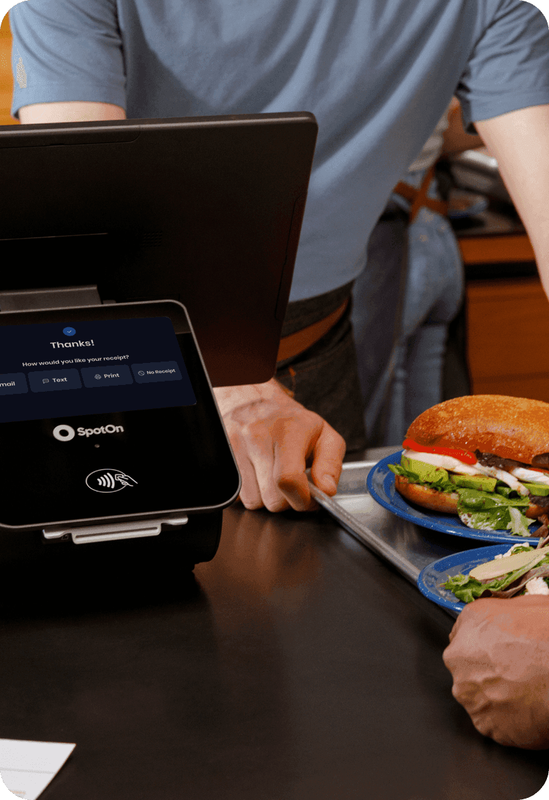 Restaurant staff using SpotOn POS at a counter-service restaurant to process an order with sandwiches and salads