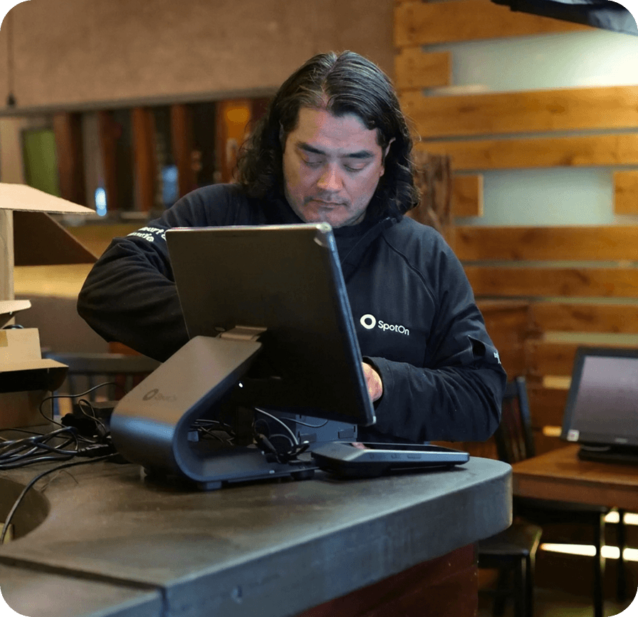 SpotOn technician sets up a POS terminal at a restaurant counter.