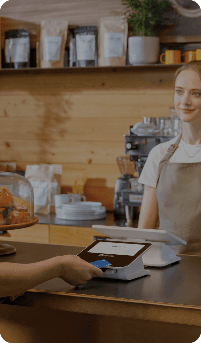 Customer at a cafe counter making a payment on the guest-facing display