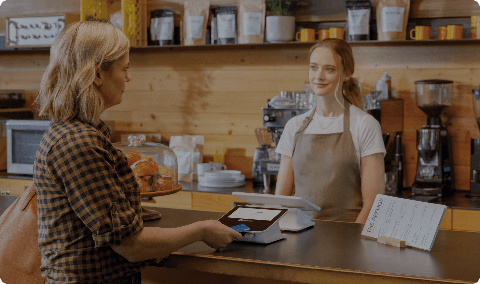Customer at a cafe counter making a payment on the guest-facing display