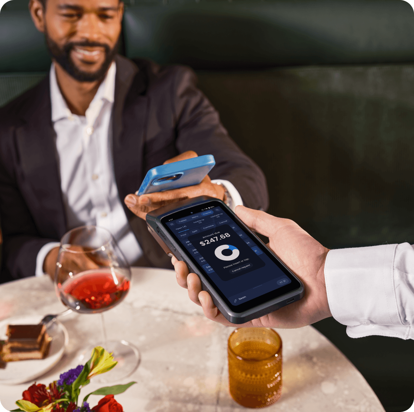 Server at a table taking a payment with SpotOn Handheld
