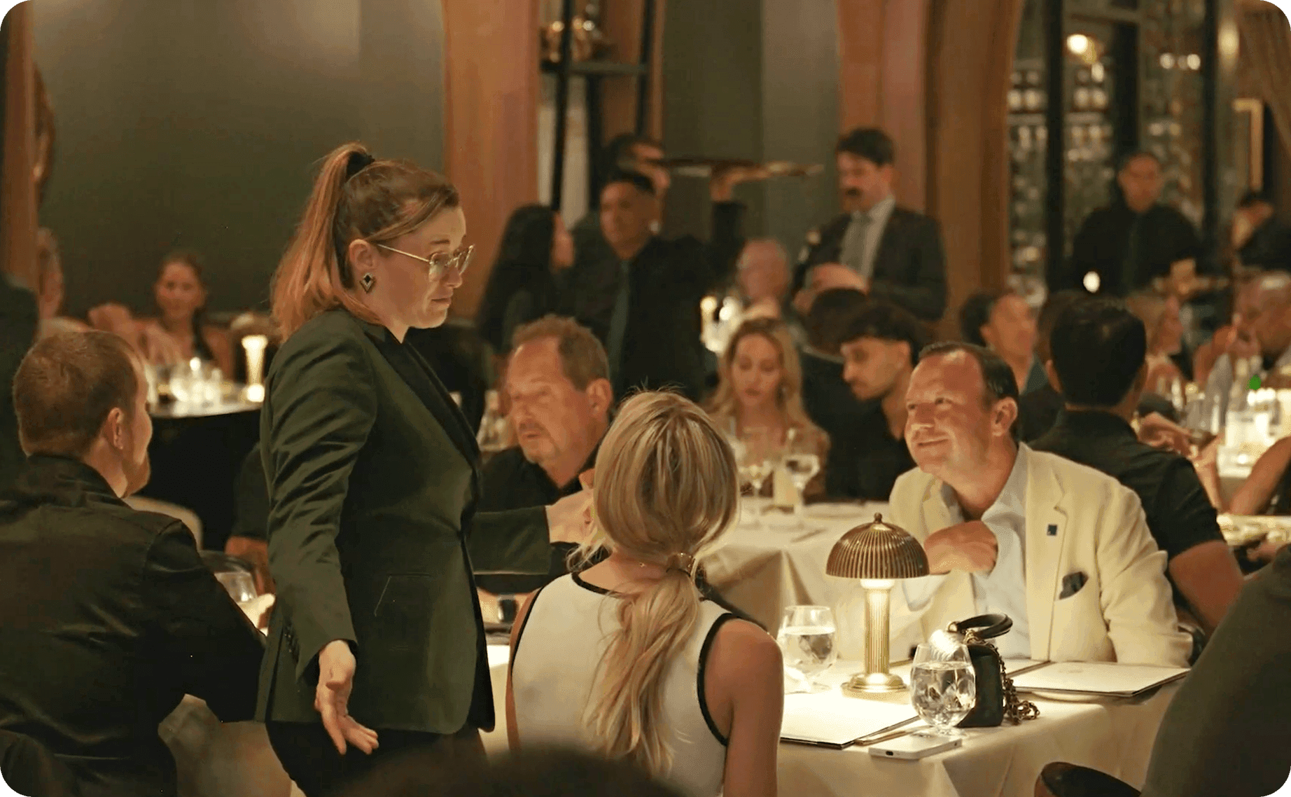 A staff member attending to a table of guests in the packed dining room at Adalina Prime
