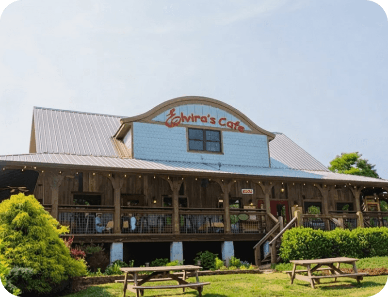 Exterior of Elvira’s Café, with a covered porch and picnic tables on the lawn