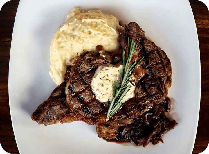 Steak and mashed potatoes on a white plate at 11th and Bay Southern Table