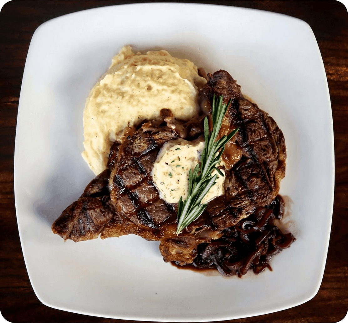 Steak and mashed potatoes on a white plate at 11th and Bay Southern Table