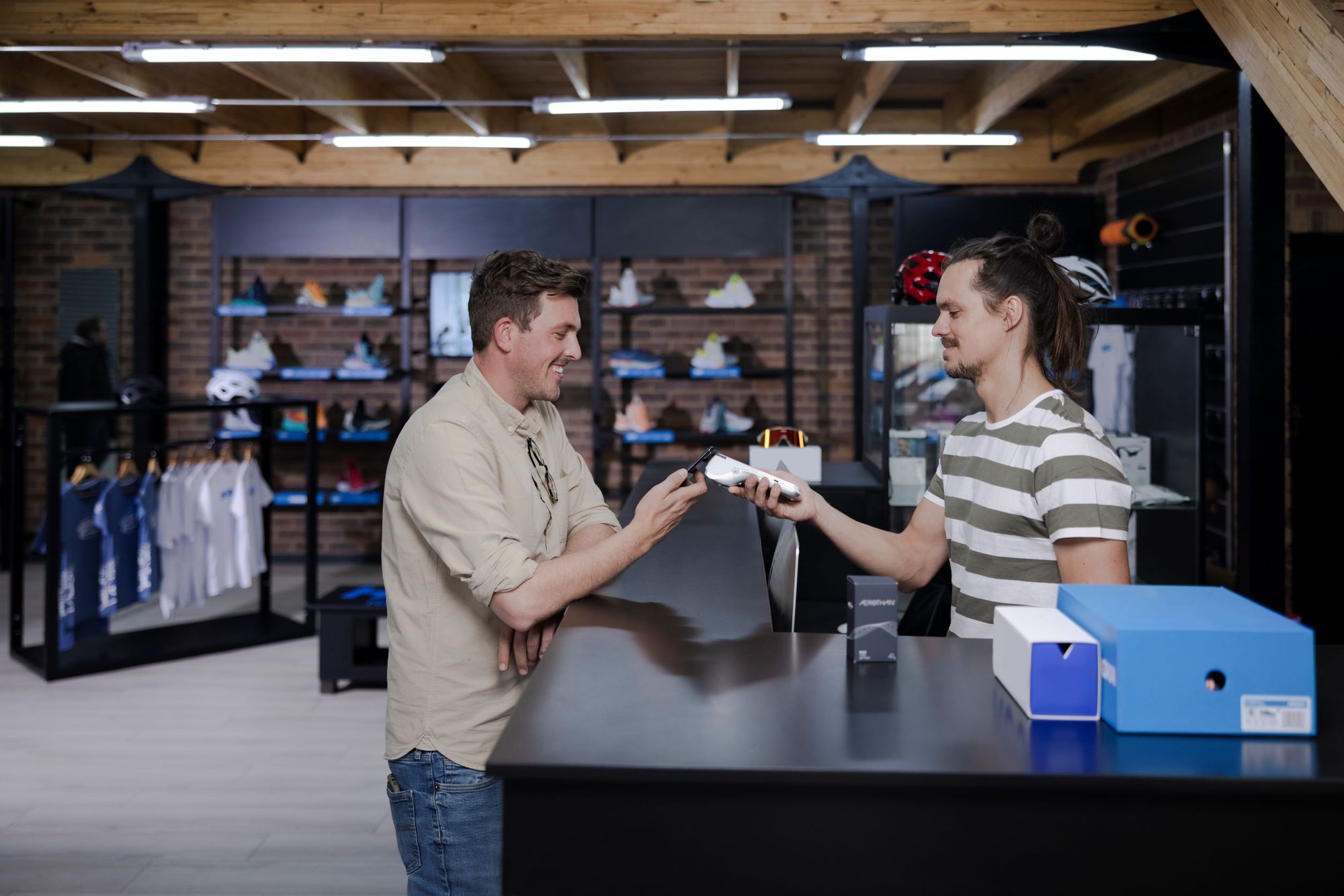 A customer taps to pay on a handheld POS at a sporting goods store.