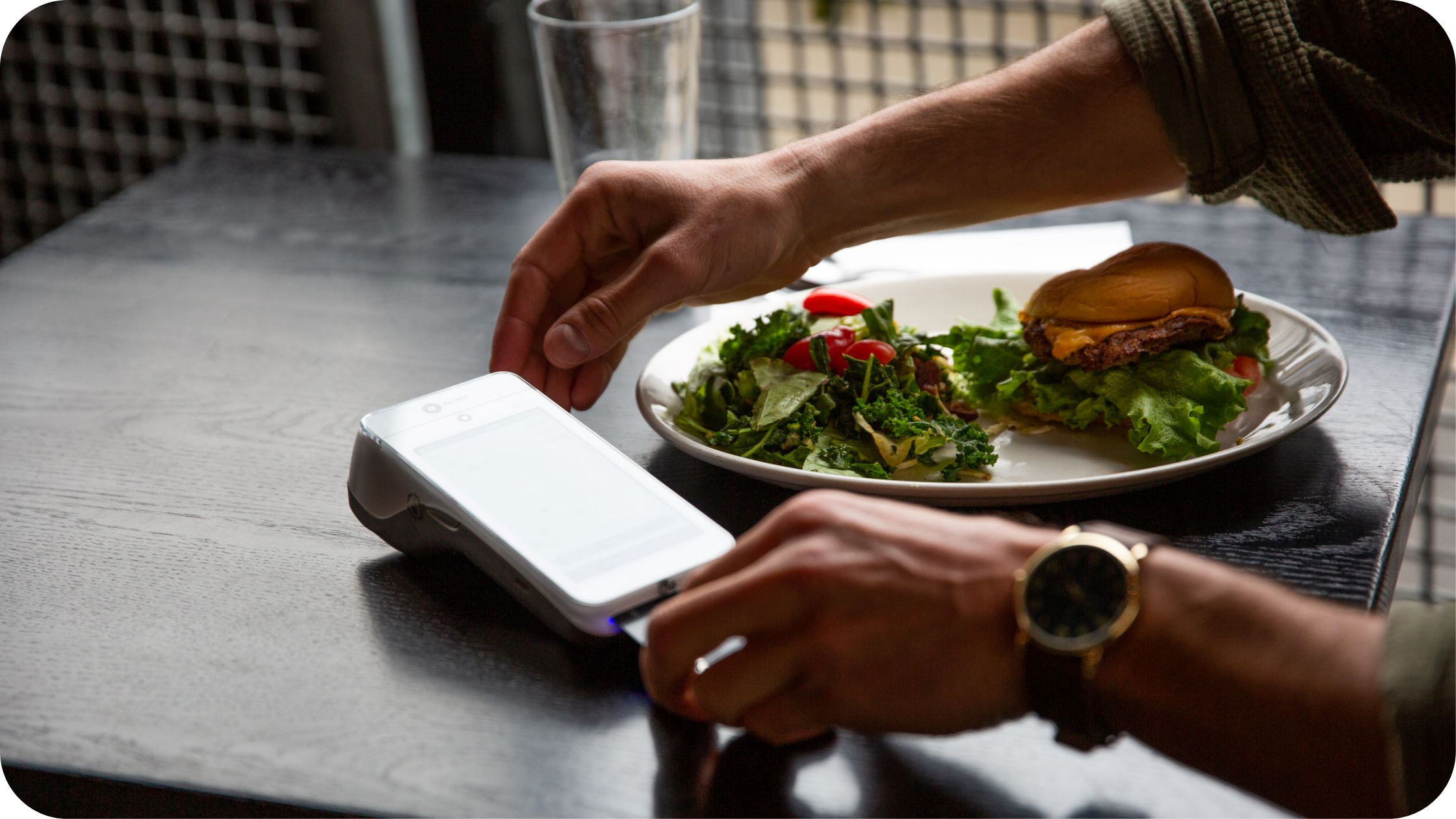 A server processing a payment at the table with a SpotOn Serve handheld.