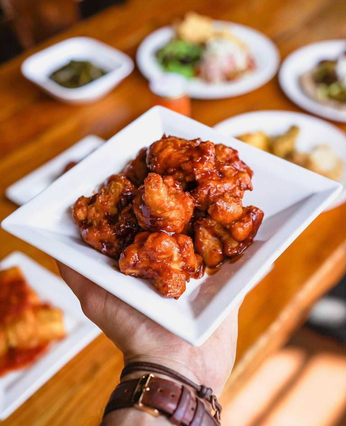 A server holds a plate of food at Majani Soulful Vegan Cuisine.