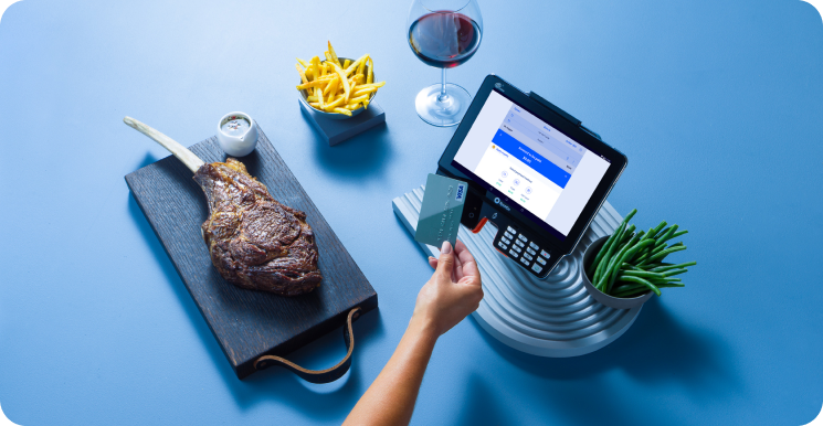 Steak, fries, and wine next to a SpotOn POS terminal.