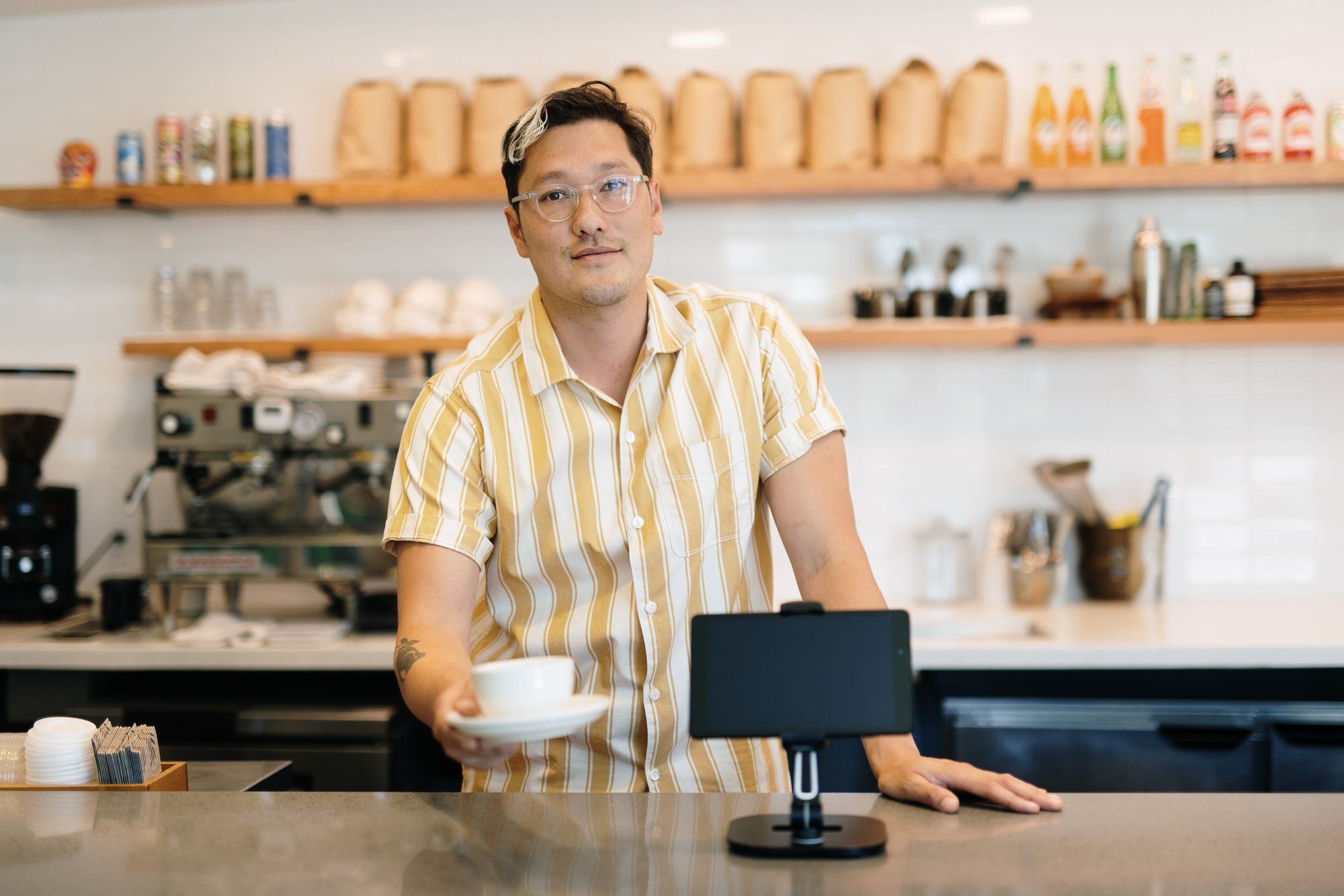 A café employee serves up a cup of coffee after completing the transaction at the point of sale.