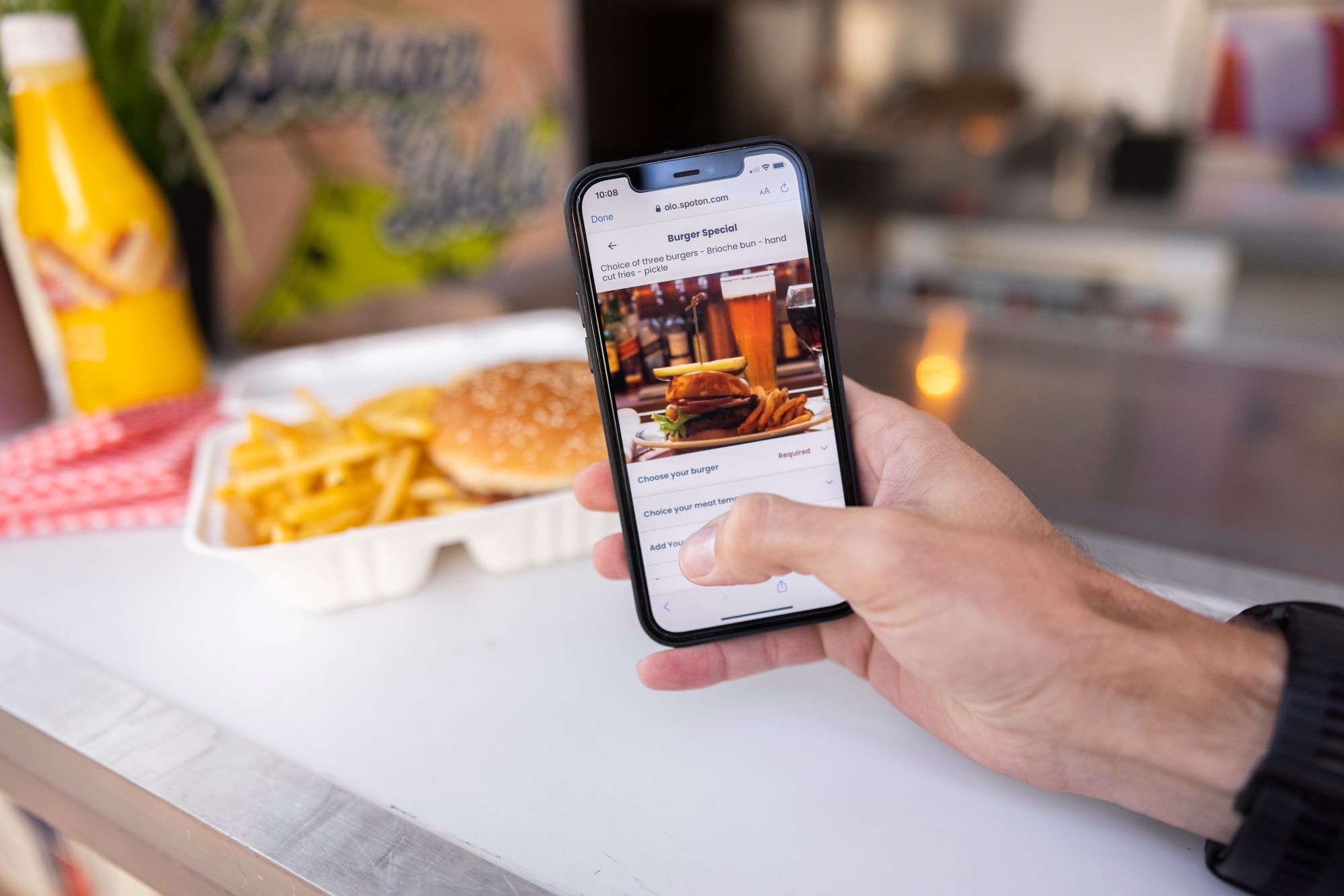 A restaurant guest orders a burger and fries with their phone.