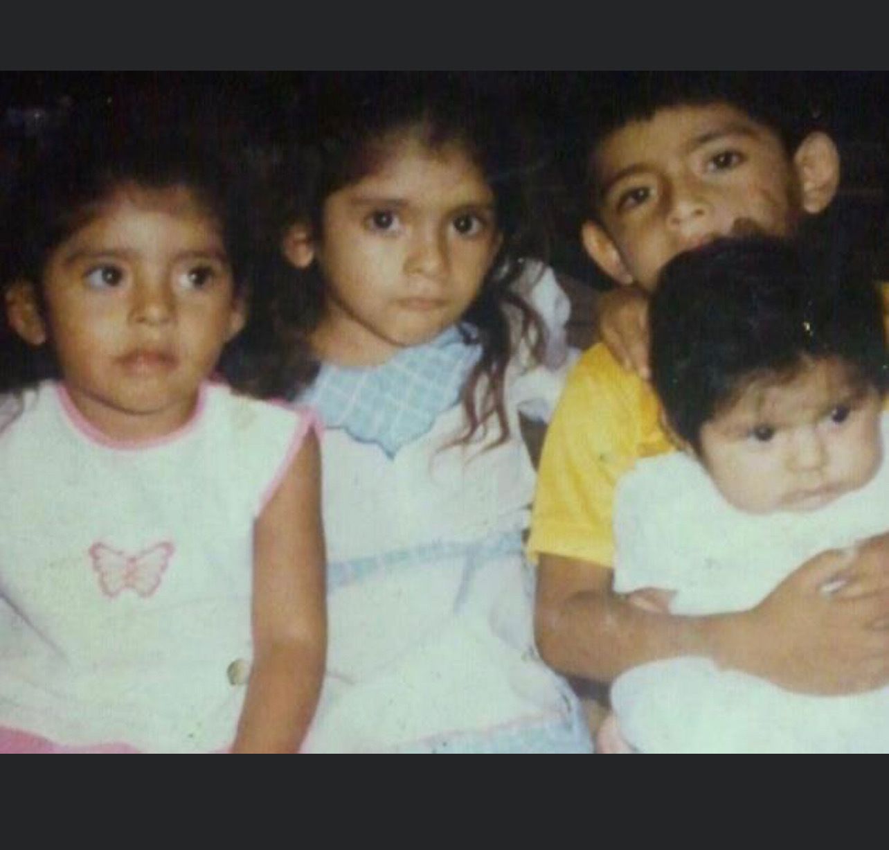 Old photograph of four children sitting.