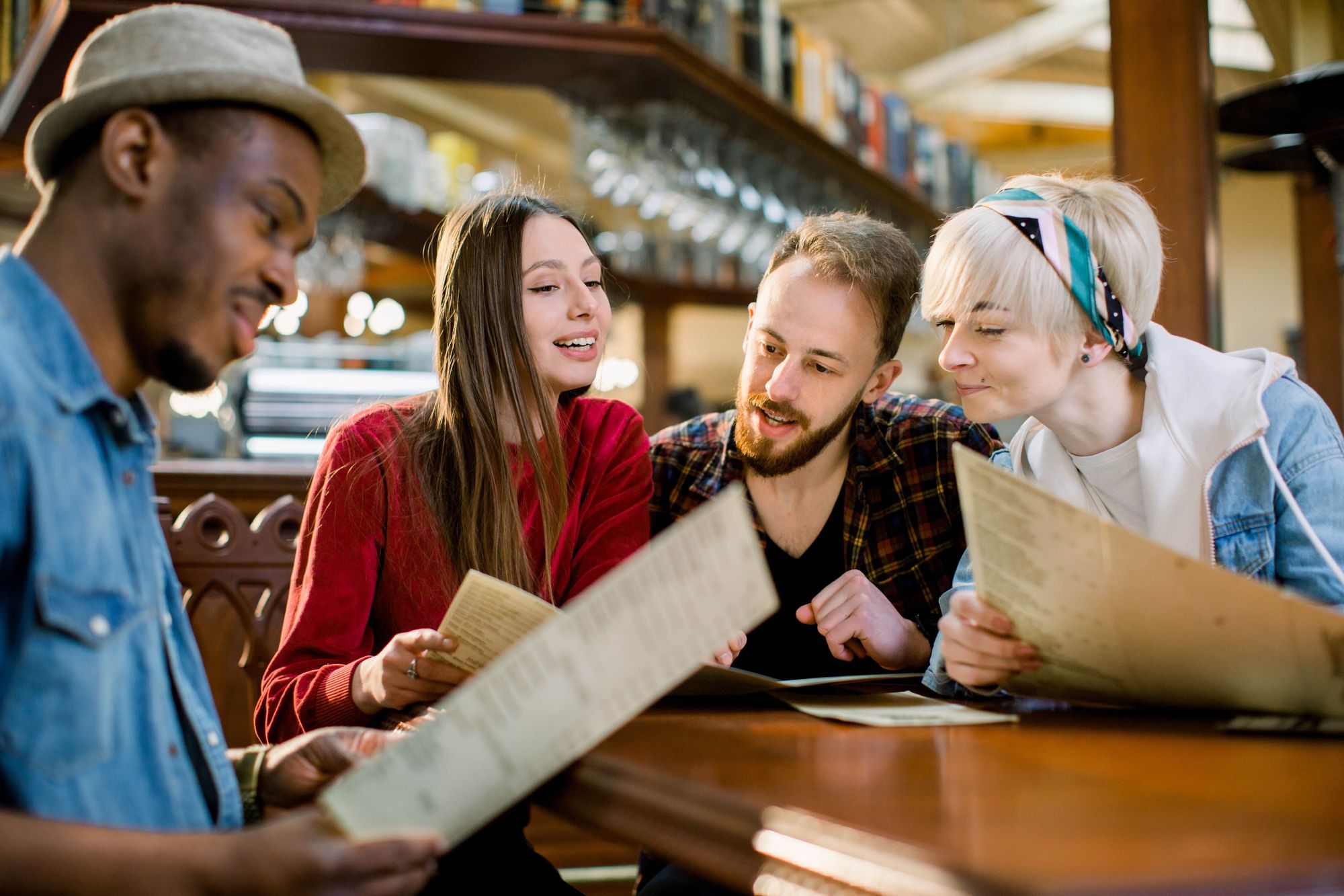 Four guests at a restaurant looking at and talking about the menu.