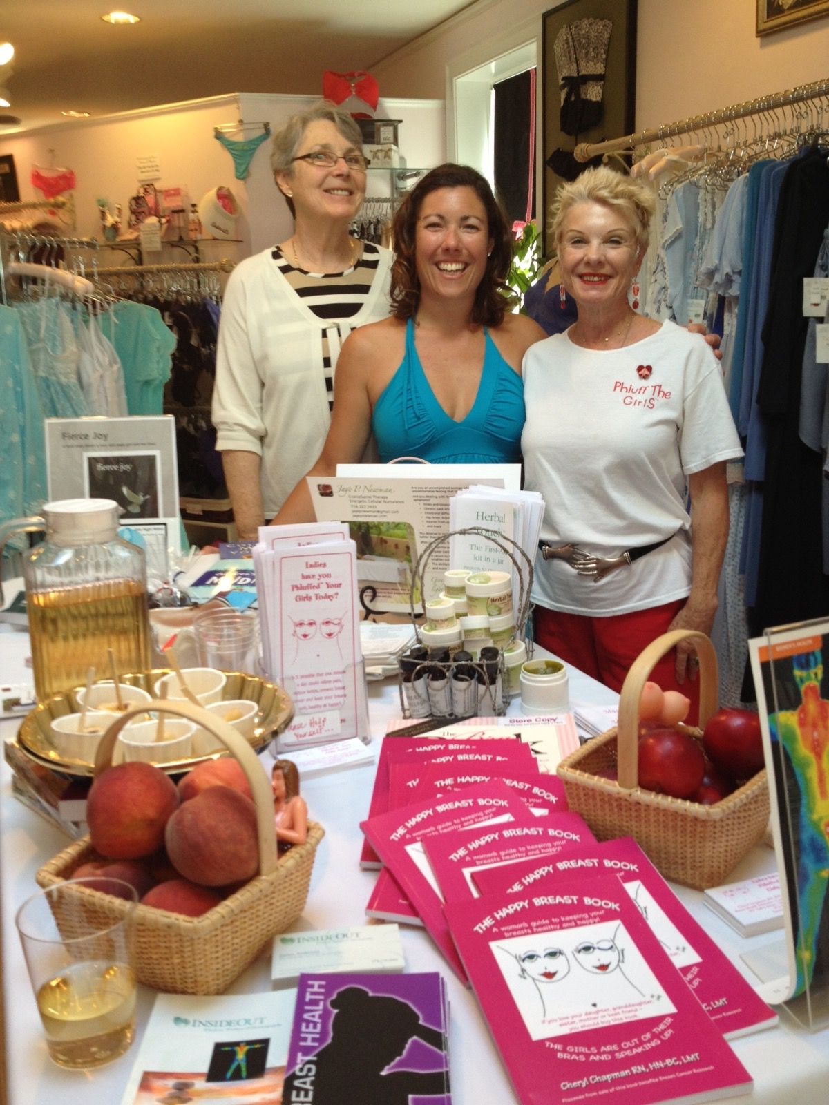 Three women stand in front of a table with brochures.